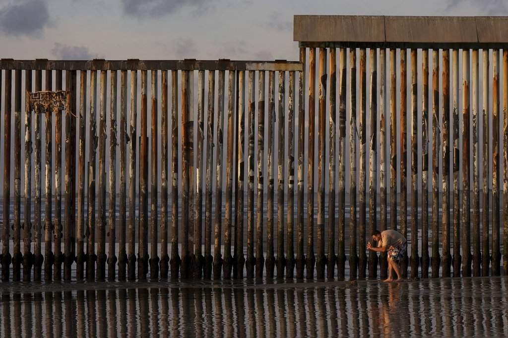 A man takes an image with his phone next to where the border wall separating Mexico and the United States reaches the Pacific Ocean Tuesday, Jan. 28, 2025, in Tijuana, Mexico. (AP Photo/Gregory Bull).