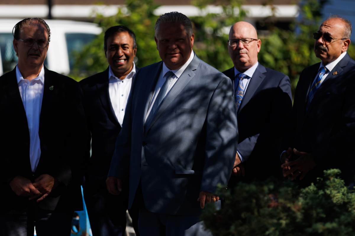 Ontario Premier Doug Ford, centre, arrives at a press conference as he’s flanked by Mississauga MPP Kaleed Rasheed, at left, and Minister of Housing Steve Clark at right, in Mississauga, Ont., Friday, Aug. 11, 2023.