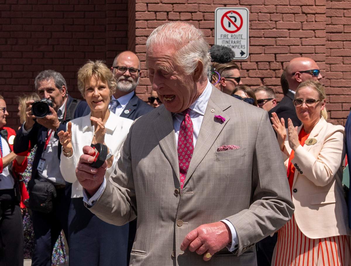 King Charles looks at the puck after participating in a ceremonial puck drop during a visit to Lansdowne Park in Ottawa on Monday, May 26, 2025. THE CANADIAN PRESS/Christinne Muschi