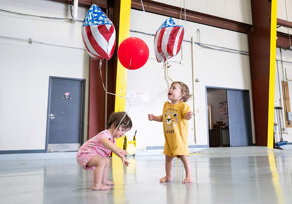 Two kids, part of the first group of Afrikaners from South Africa to arrive for resettlement play with balloons after they arrived at Washington Dulles International Airport in Dulles, Virginia, on May 12, 2025.