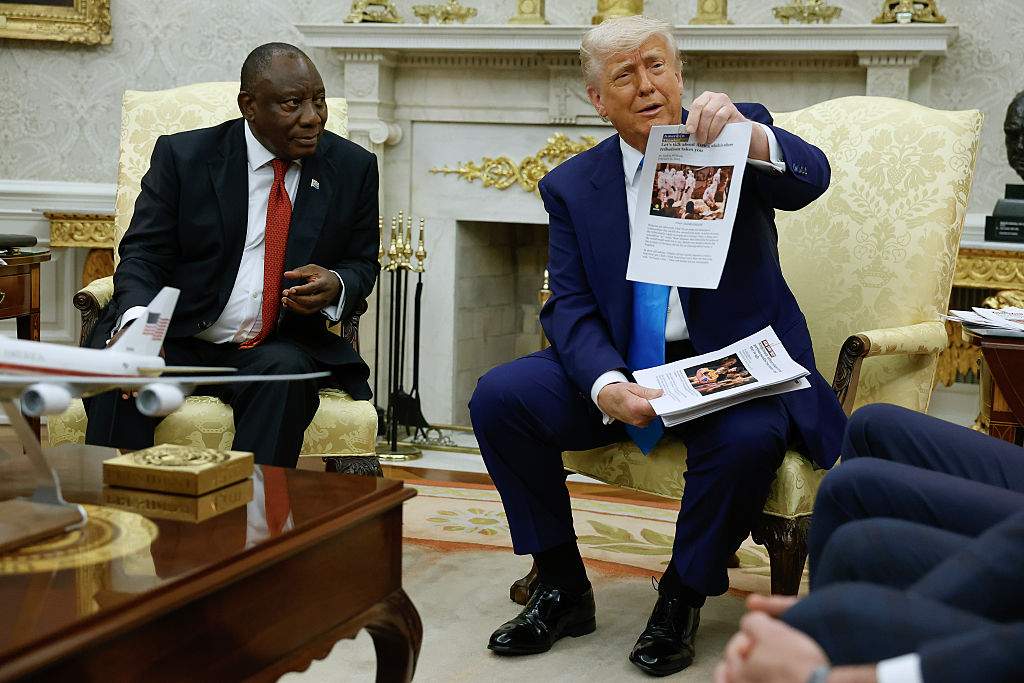 U.S. President Donald Trump holds up a printed article from "American Thinker" while accusing South Africa President Cyril Ramaphosa of state-sanctioned violence against white farmers in South Africa during a press availability in the Oval Office at the White House on May 21, 2025 in Washington, DC.