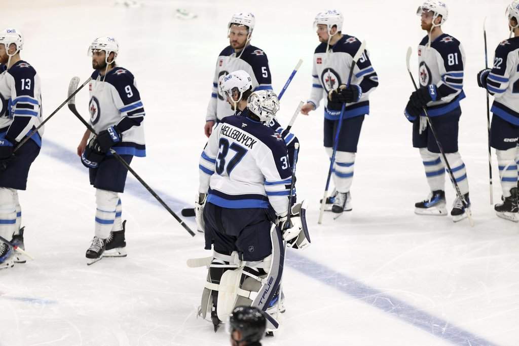Winnipeg Jets goalie Connor Hellebuyck (37) and forward Mark Scheifele (55) join the handshake line after their overtime loss to the Dallas Stars in Game 6 of a second-round NHL playoff series in Dallas on Saturday, May 17, 2025. (AP Photo/Gareth Patterson).