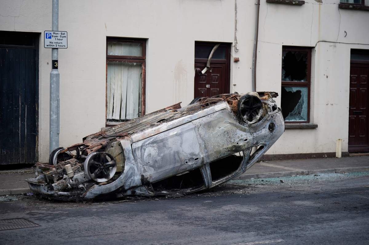 A burnt-out overturned car on the street following a second night of violence during a protest over an alleged sexual assault in the Co Antrim town, in Ballymena, Northern Ireland, Wednesday June 11, 2025. (Niall Carson/PA via AP).