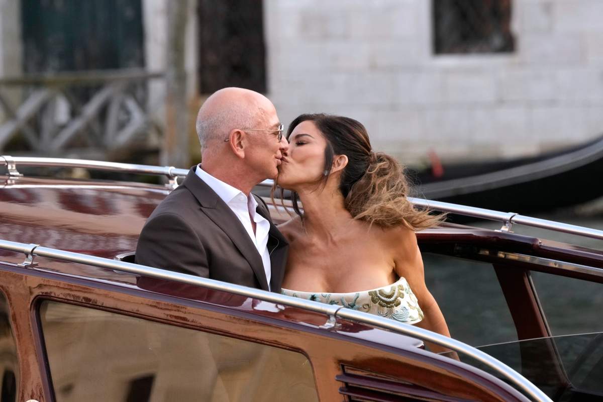 Jeff Bezos, center left, and Lauren Sanchez, center right, kiss as they leave a hotel for their pre wedding reception, in Venice, Italy, Thursday, June 26, 2025.