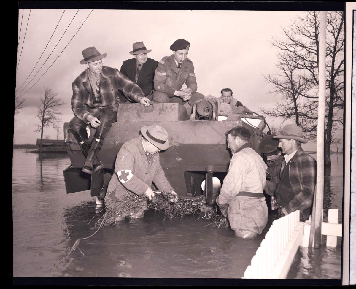 A group of men work to get a fence out of the propeller of a piece of flood-fighting equipment.