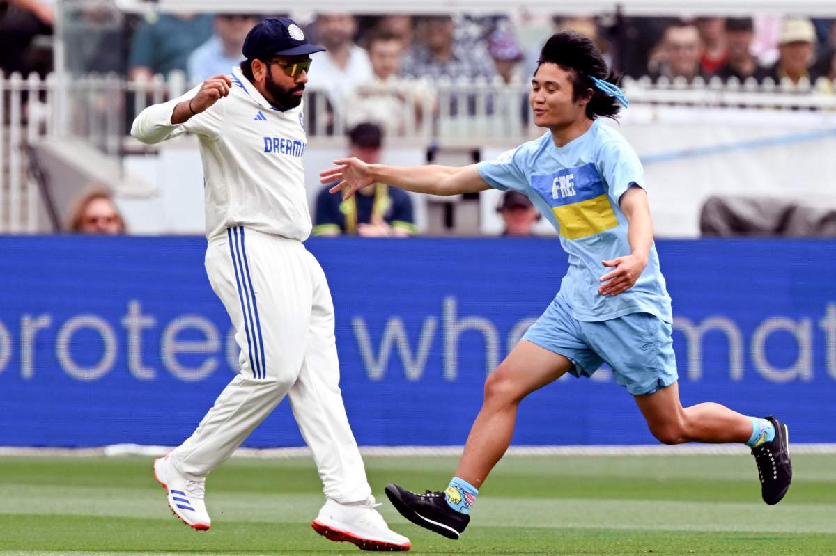 A pitch invader (R) runs past India's captain Rohit Sharma on the second day of the fourth cricket Test match between Australia and India at the Melbourne Cricket Ground (MCG) in Melbourne on December 27, 2024.