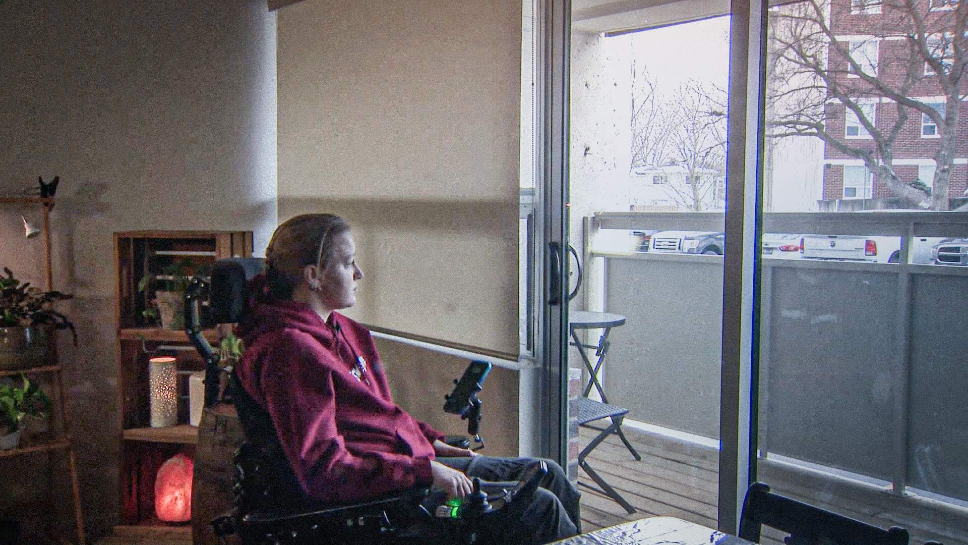 Photo of Kayla Pollock sitting in wheelchair and looking out window