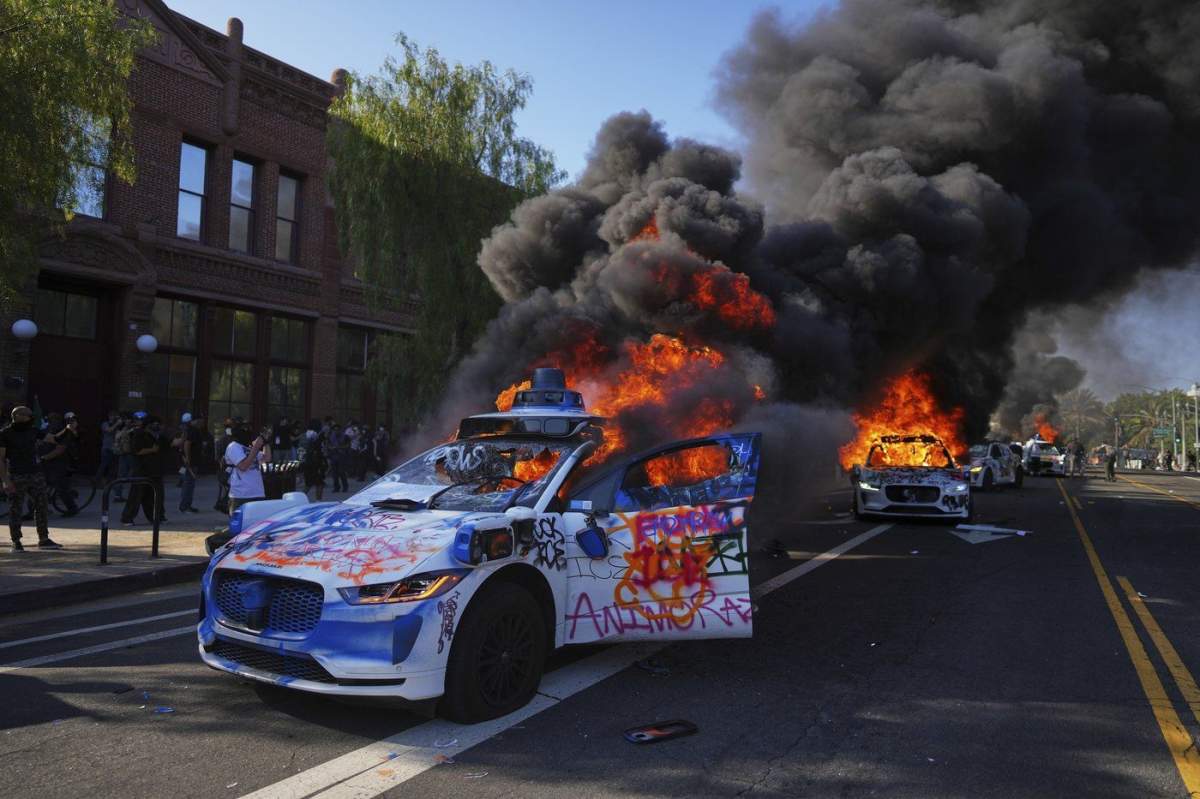 Multiple Waymo taxis burn near the Metropolitan Detention Center of downtown Los Angeles on Sunday, June 8, 2025, following the immigration raid protest.