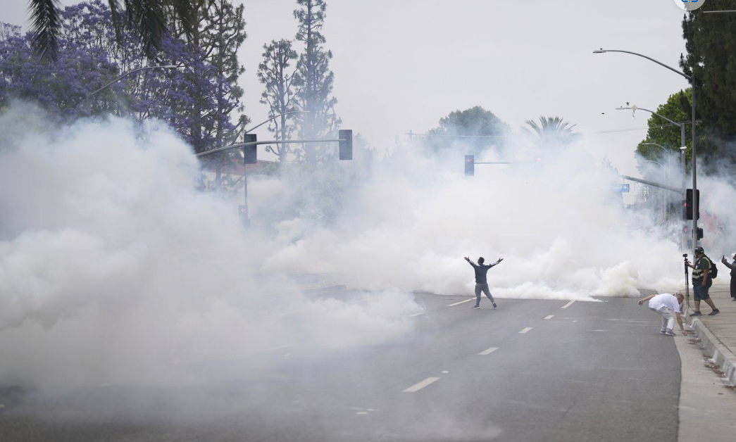 Smoke fills the street as protesters confront Border Patrol personnel during a demonstration over the dozens detained in an operation by federal immigration authorities a day earlier in Paramount section of Los Angeles Saturday.