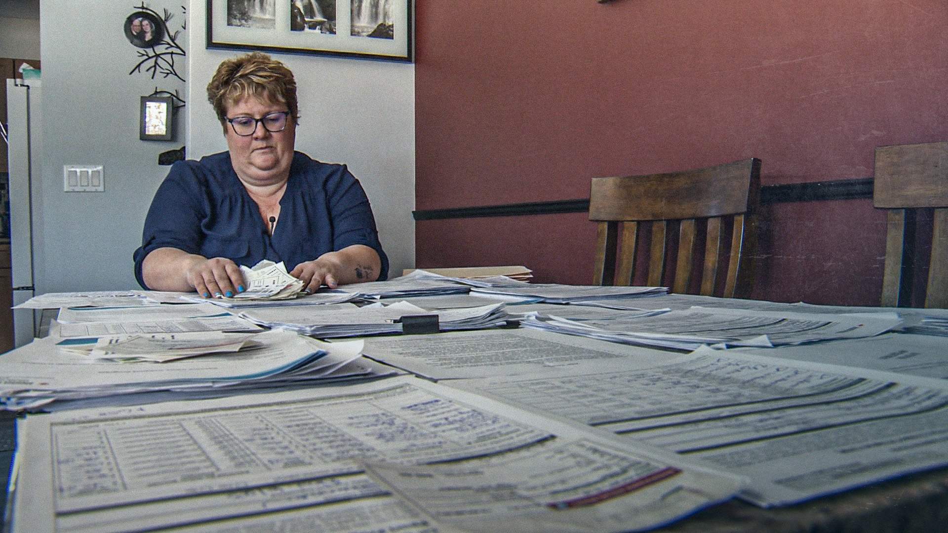 Photo of vaccine injured Shannon Dupont with program mail and documents spread across her entire dining room table.