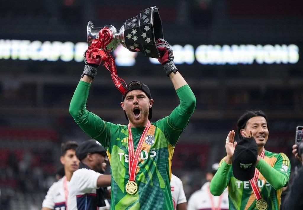 Vancouver Whitecaps goalkeeper Isaac Boehmer, front left, hoists the Voyageurs Cup as goalkeeper Yohei Takaoka, back right, applauds after Vancouver defeated Toronto FC on penalty kicks during the Canadian Championship final soccer match, in Vancouver, on Wednesday, September 25, 2024. THE CANADIAN PRESS/Darryl Dyck