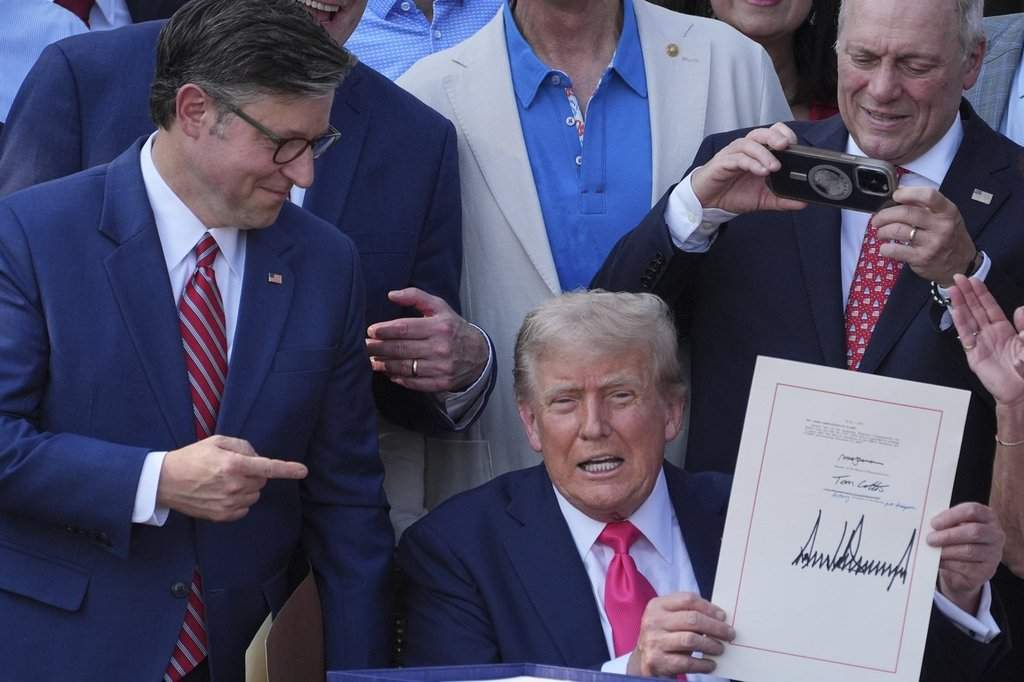 House Speaker Mike Johnson of La., points to President Donald Trump after he signed his signature bill of tax breaks and spending cuts at the White House, Friday, July 4, 2025, in Washington, surrounded by members of Congress.