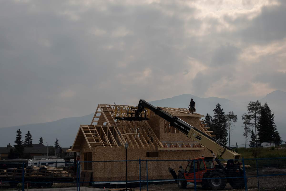Builders work on a new construction on a block that was burned down, roughly one year after the wildfire in Jasper, Alta., on Monday, July 21, 2025.
