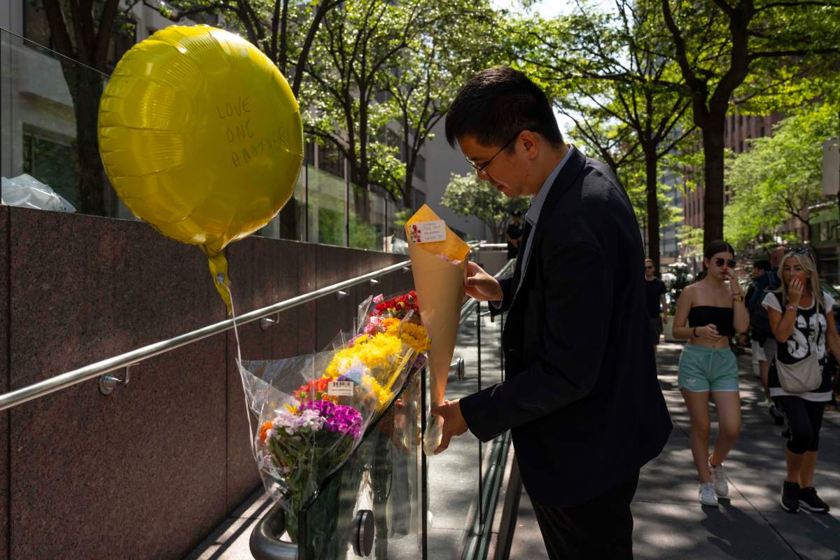 A person leaves flowers at a makeshift memorial outside scene of Monday's deadly shooting, Tuesday, July 29, 2025, in New York.