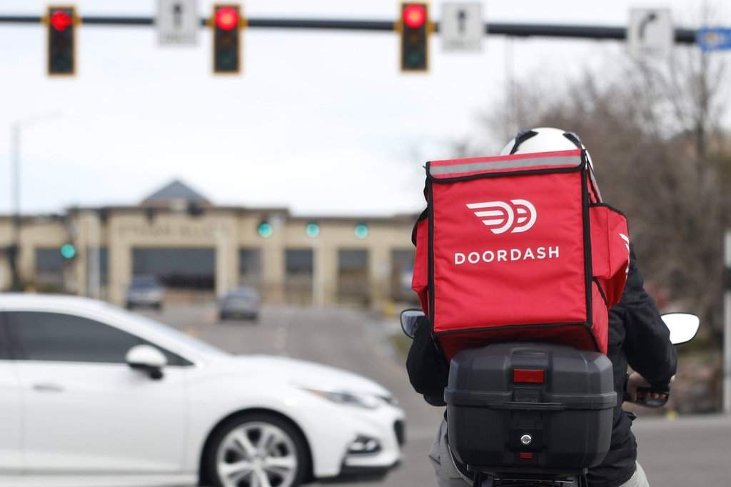 A food delivery rider waits for the traffic light to change Monday, March 30, 2020, in Lone Tree, Colo.   