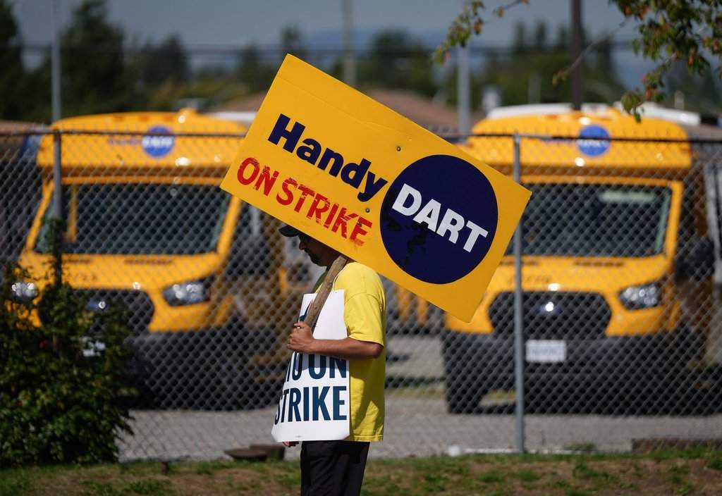 A striking HandyDART transit system worker walks a picket line in Surrey, B.C., on Thursday, September 5, 2024. THE CANADIAN PRESS/Darryl Dyck.