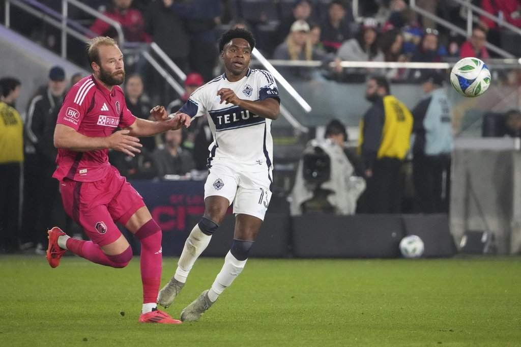 St. Louis City's João Klauss, left, and Vancouver Whitecaps' Ralph Priso (13) challenge for the ball during the second half of an MLS soccer match Saturday, April 19, 2025, in St. Louis. (AP Photo/Jeff Roberson).
