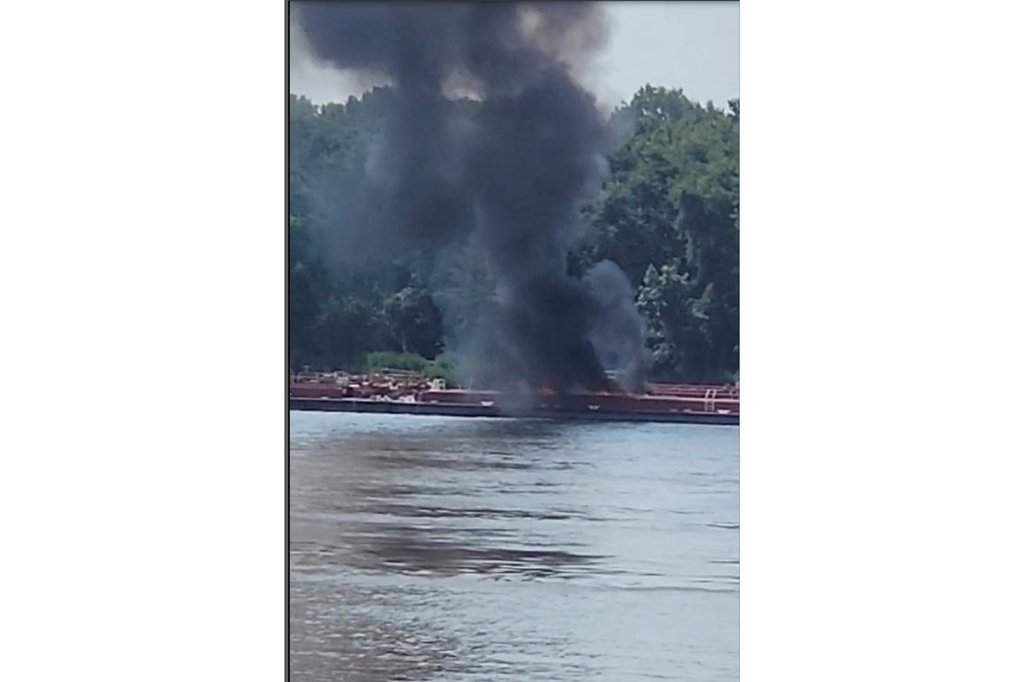 This image provided by Adam Briggs shows smoke fills the air from a barge after a helicopter crash in the Mississippi River near Alton, Ill., on Thursday, Aug. 7, 2025.