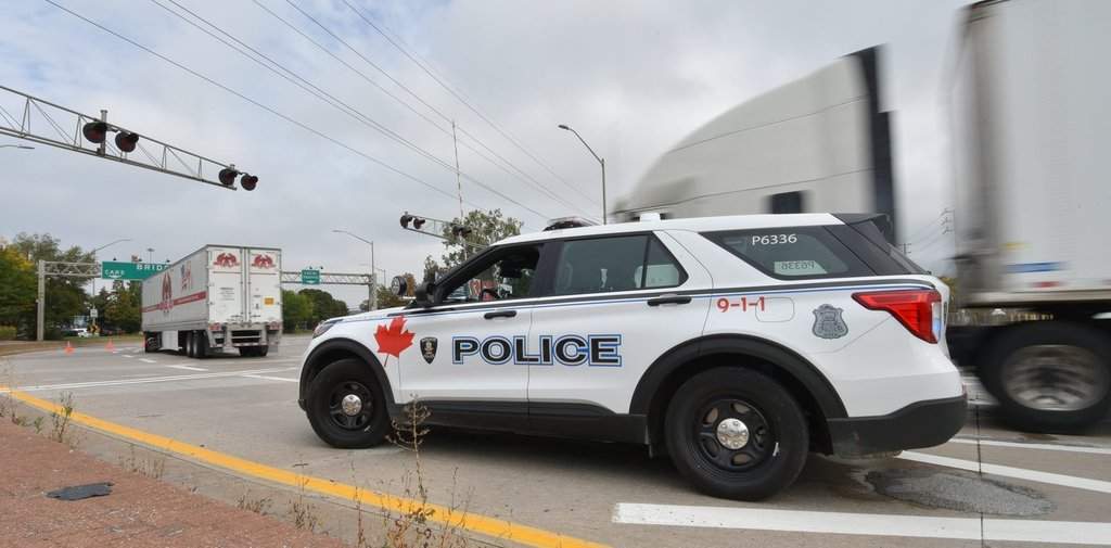 A police vehicle is on the scene as trucks make their way to the Ambassador Bridge border crossing in Windsor, Ont., Monday, Oct.4, 2021. THE CANADIAN PRESS/Rob Gurdebeke.