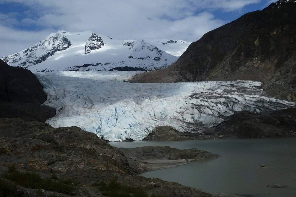 FILE - A canoe, bottom right, glides on Mendenhall Lake, in front of the Mendenhall Glacier, on Sunday, May 18, 2025, in Juneau, Alaska. (AP Photo/Becky Bohrer, File).