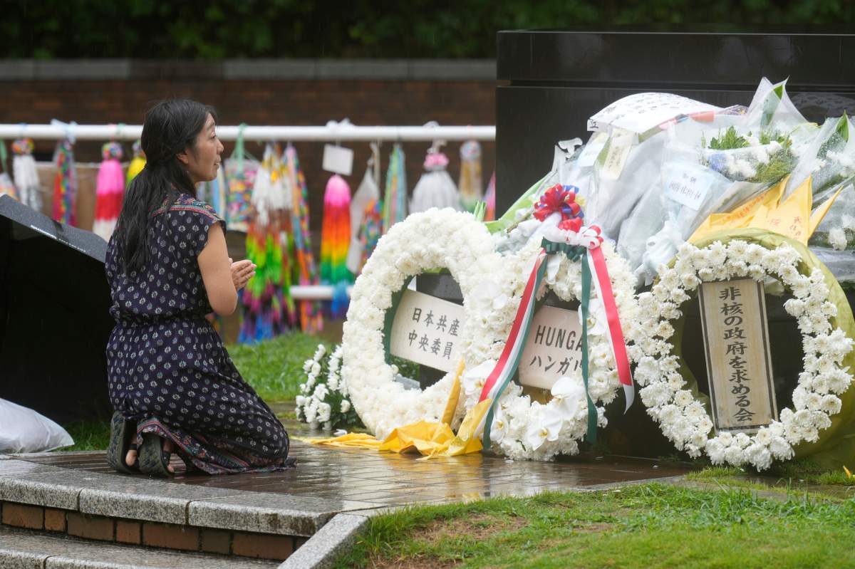 A woman offers prayer in the rain at the Atomic Bomb Hypocenter Park, as Japan commemorates the 80th anniversary of the day an atomic bomb was dropped on its southwestern city, in Nagasaki, Japan Saturday, Aug. 9, 2025.