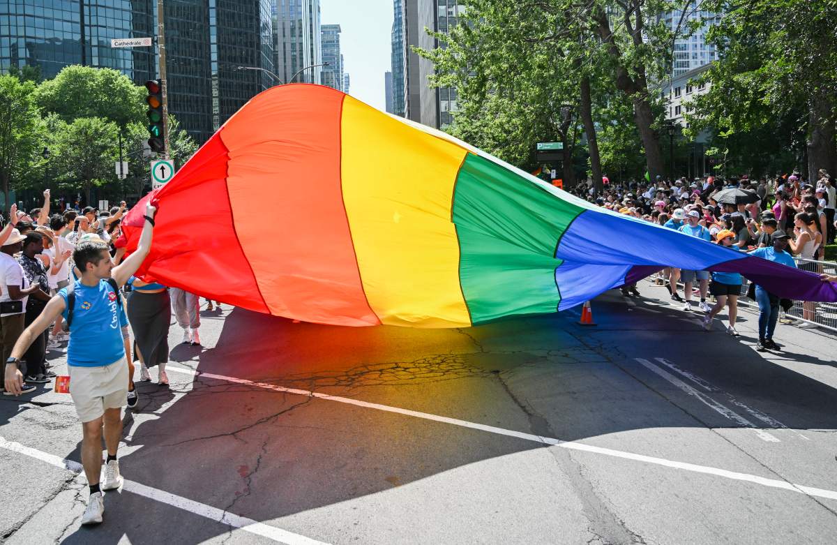Participants pull a rainbow flag along a street during the Pride parade in Montreal, Sunday, August 10, 2025. 