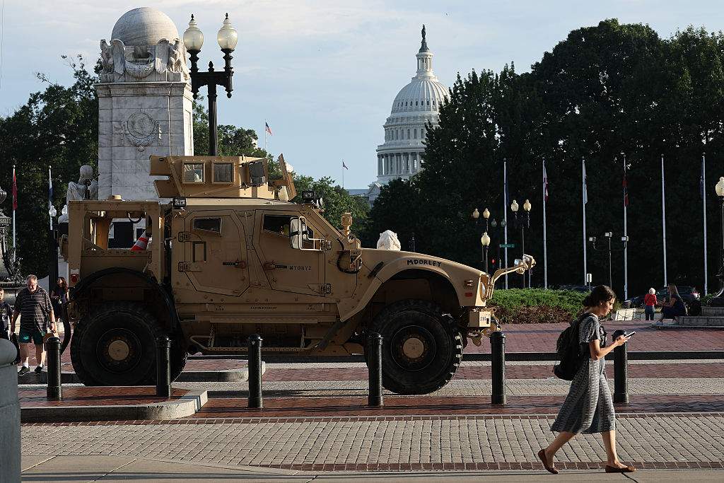 Pedestrians pass an MRAP (Mine Resistant Ambush Protected Vehicles) combat vehicle deployed by the Washington DC National Guard outside Union Station on August 14, 2025 in Washington, DC. President Donald Trump announced plans to deploy federal officers and the National Guard to the District while placing the DC Metropolitan Police Department under federal control and assist in crime prevention in the nation's capital.