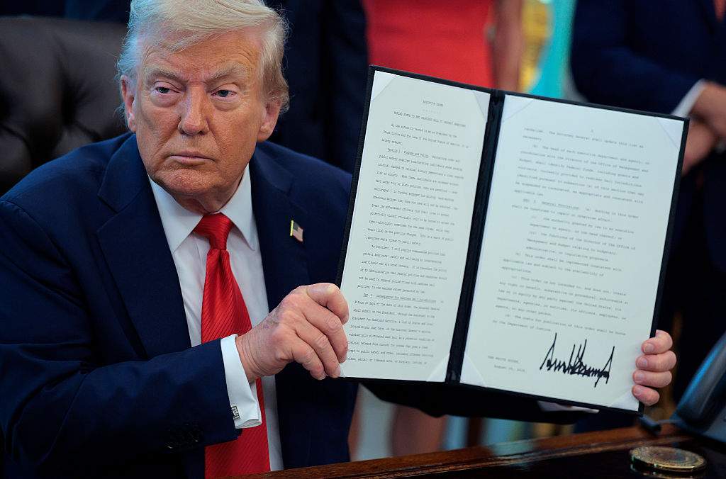 U.S. President Donald Trump signs executive orders in the Oval Office at the White House on August 25, 2025 in Washington, DC. Furthering his federal takeover of the capital city’s law enforcement, Trump signed orders ending cashless bail in the District of Columbia, mandating prosecution for people who desecrate the American flag -- including by burning it -- and other orders.