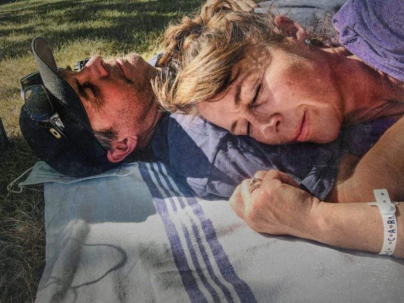 Carol Messenger and her husband eyes closed and lying on blanket on lawn of hospital in 2021