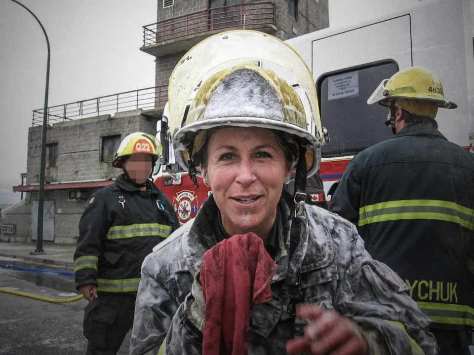 A phot of Carol Messenger in full fire protection gear at a training center.