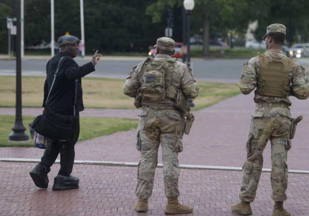 Armed members of the South Carolina National Guard talk with a man while positioned outside of Union Station in Washington, Sunday, Aug. 24, 2025.