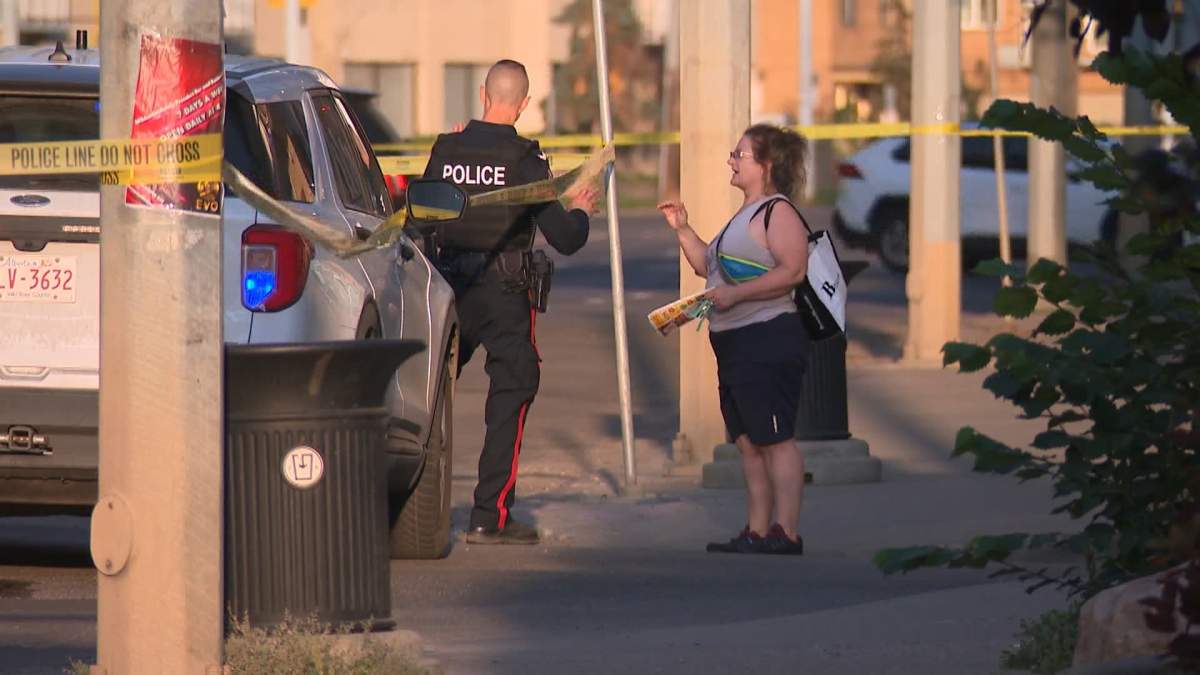An investigator is seen speaking with a woman along Jasper Avenue in Edmonton as police search for more information on a shooting early Saturday morning.