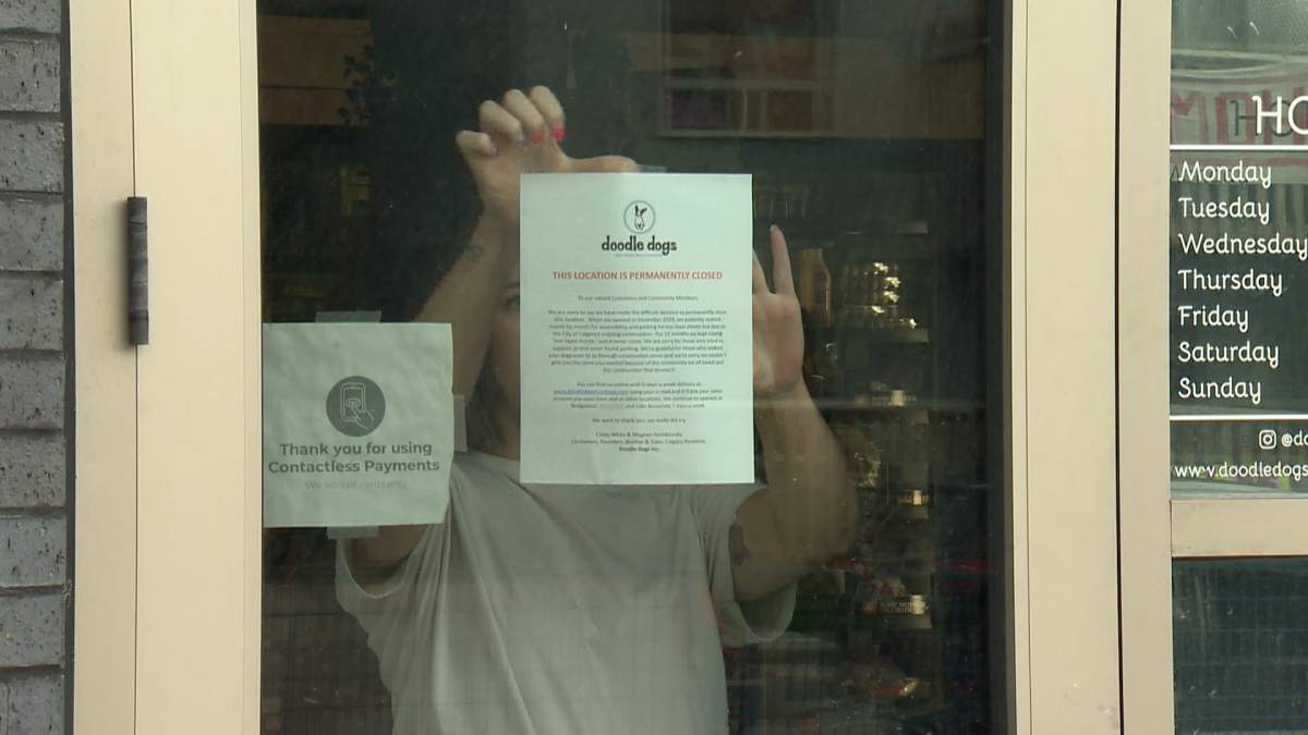 Meghan Huchkowski, who owns Doodle Dogs with her brother, places a note in the window of the Marda Loop store, telling customers the business is closing its doors for good.