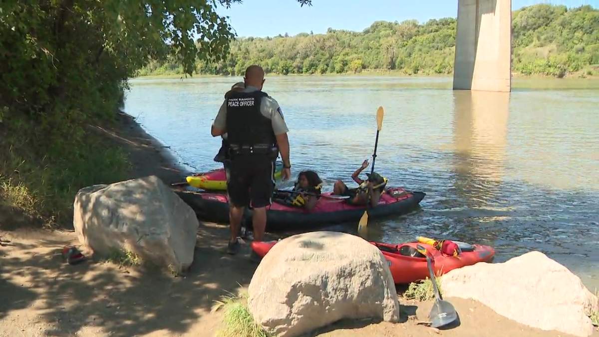 A City of Edmonton park ranger speaking with kayakers wearing their life jackets at the Capilano boat launch on the North Saskatchewan River on July 31, 2025.