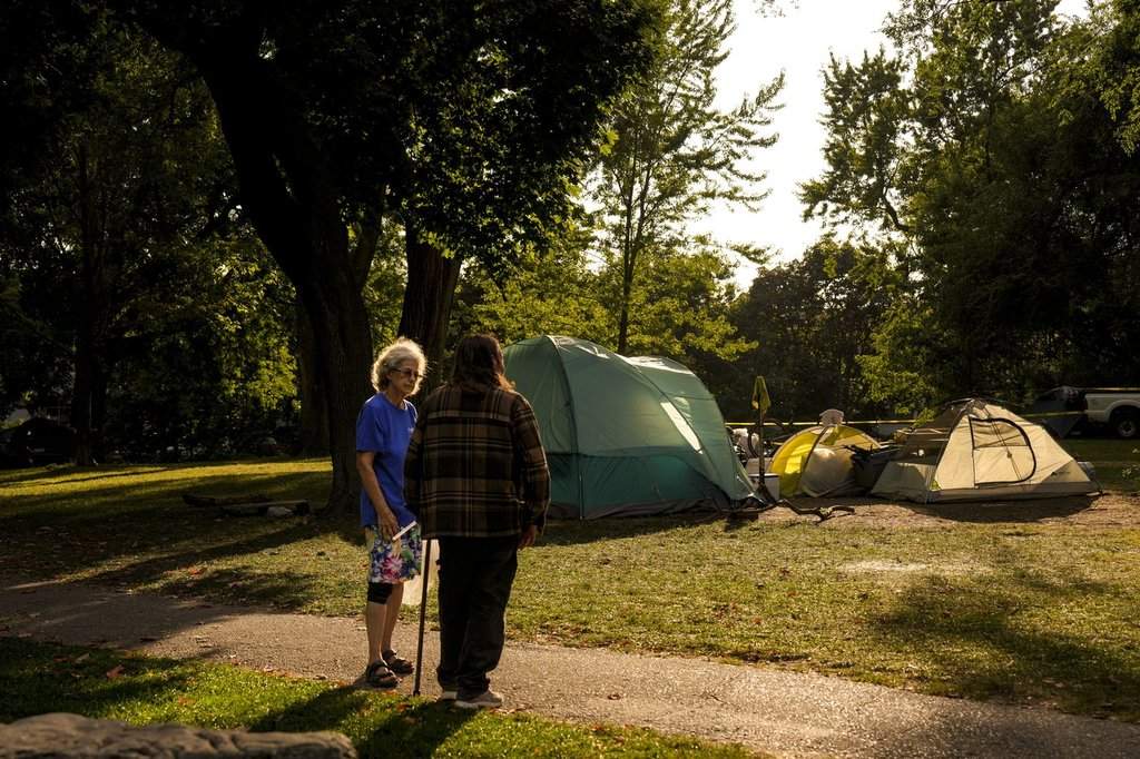 A local resident talks to a passer-by in front of an encampment at Dufferin Grove Park in Toronto on Wednesday September 17, 2025. 