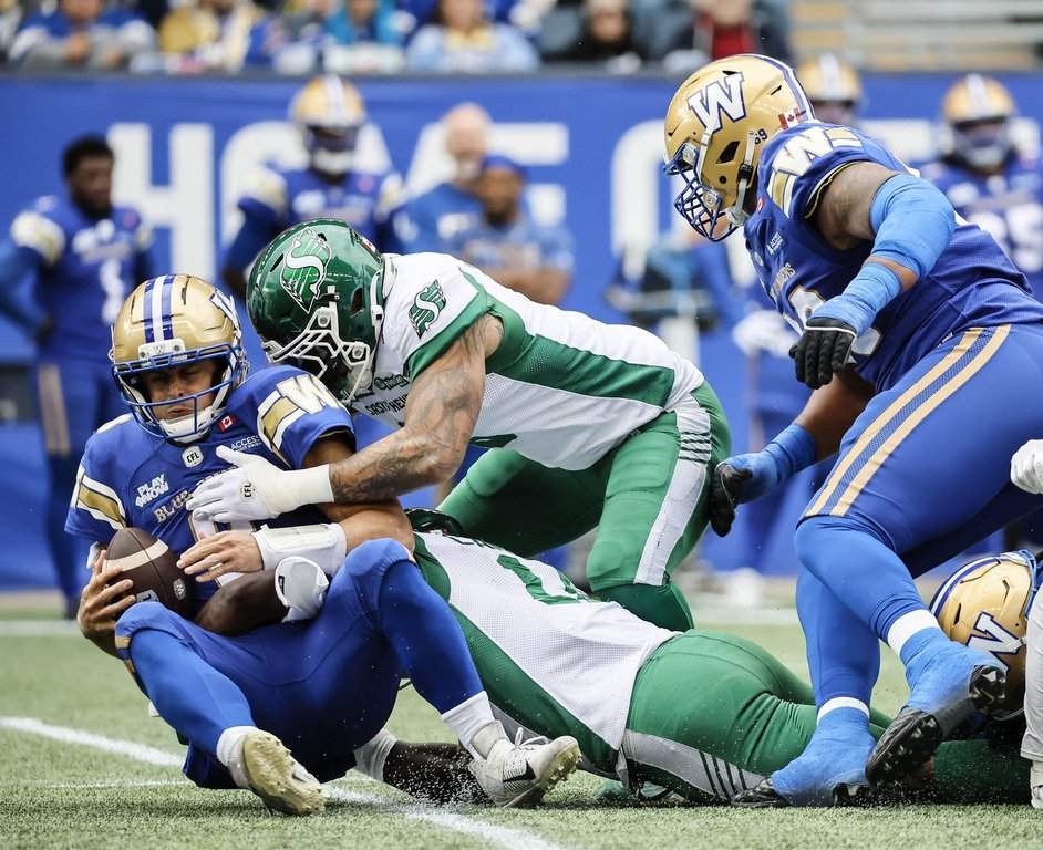 Winnipeg Blue Bombers quarterback Zach Collaros (8) gets sacked by Saskatchewan Roughriders' Malik Carney (11) and Shane Ray (5) during first half CFL action in Winnipeg,