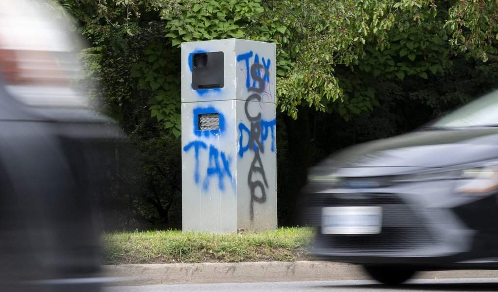 Cars zoom past a vandalized traffic speed camera beside High Park in Toronto on Thursday August 24, 2023.