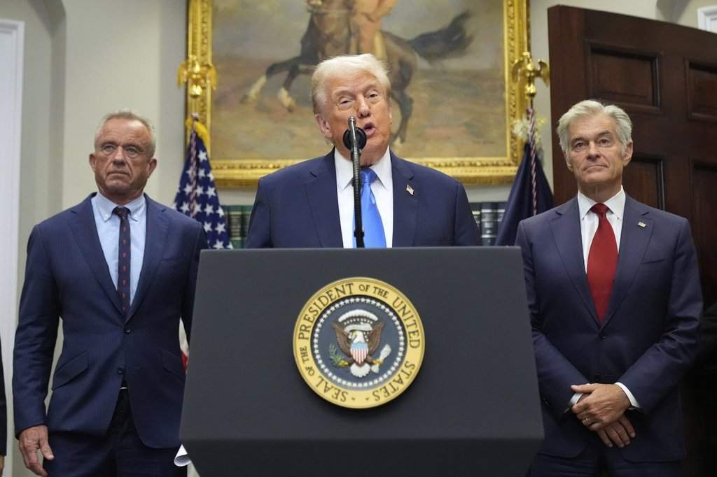President Donald Trump speaks in the Roosevelt Room of the White House, Monday, Sept. 22, 2025, in Washington, as Health and Human Services Secretary Robert F. Kennedy Jr., left, and Centers for Medicare & Medicaid Services administrator Dr. Mehmet Oz listen. (AP Photo/Mark Schiefelbein).