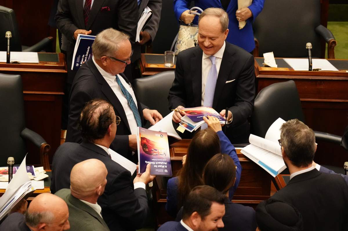 Ontario Finance Minister Peter Bethlenfalvy autographs copy of the budget after delivering it at the Queen's Park Legislature in Toronto, on Thursday, May 15, 2025. 