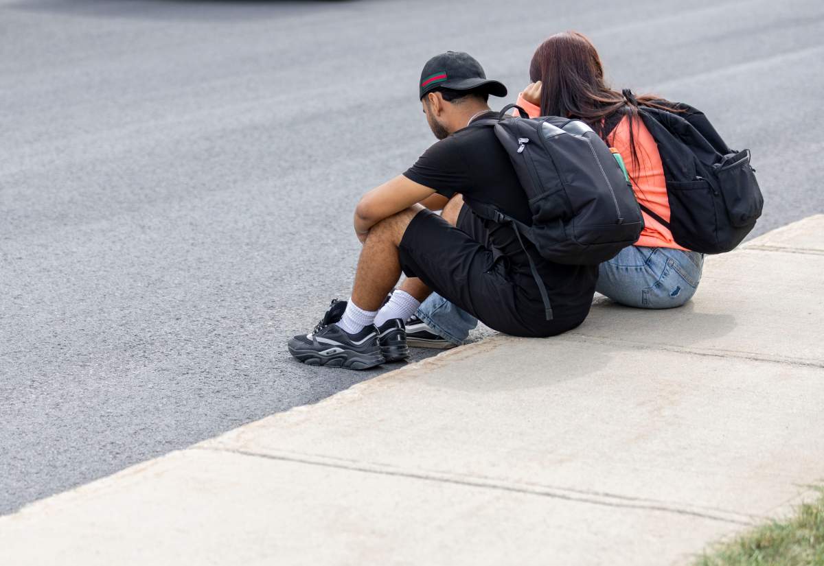Local teenagers sit on the street where one person died after being shot by police on Montreal’s South Shore of Longueuil, Que., on Monday, September 22, 2025.