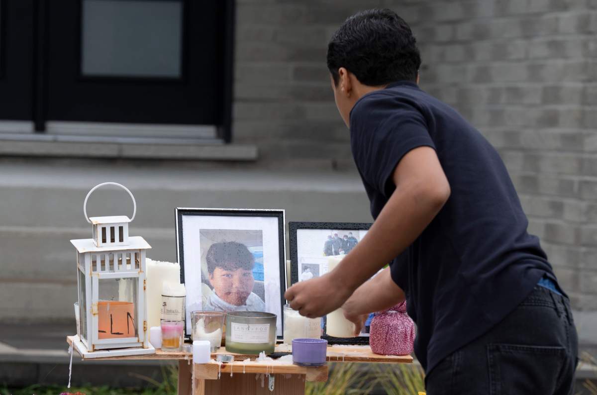 A teenager light candles and pay respects at the memorial site for classmate Nooran Rezayi, who was killed on Sunday afternoon after police responded to a report of a group of armed people in a quiet suburban neighbourhood in Longueuil, Que., south of Montreal on Thursday, September 25, 2025.  