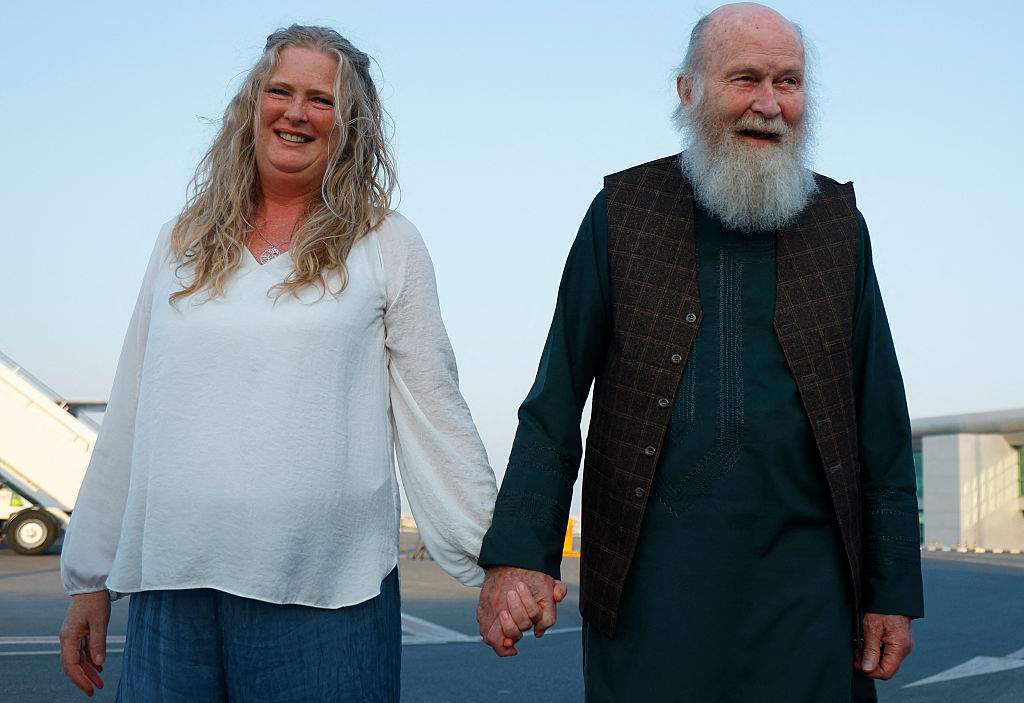 Peter Reynolds (R) holds the hands of his daughter Sarah Entwistle after landing at the airport in Doha on September 19, 2025.