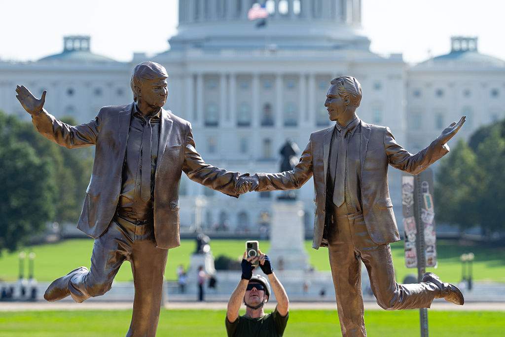 A cyclist stops to take photos of a statue featuring President Donald Trump and Jeffrey Epstein dancing, titled "In Honor of Friendship Month," that appeared on the east end of the National Mall in Washington on Tuesday morning, September 23, 2025.