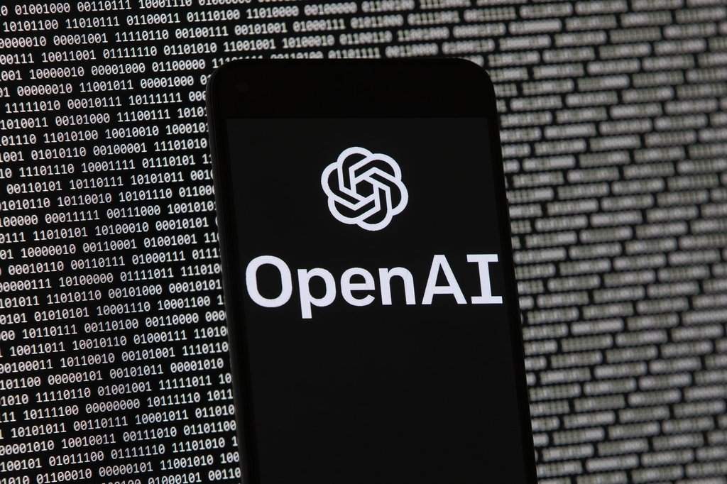 FILE - The OpenAI logo appears on a mobile phone in front of a computer screen with random binary data, March 9, 2023, in Boston. (AP Photo/Michael Dwyer, File).