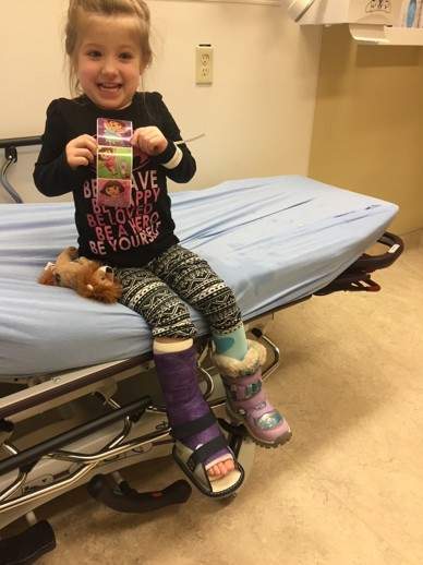 Little girl shows off leg cast, and stickers in a doctor's office