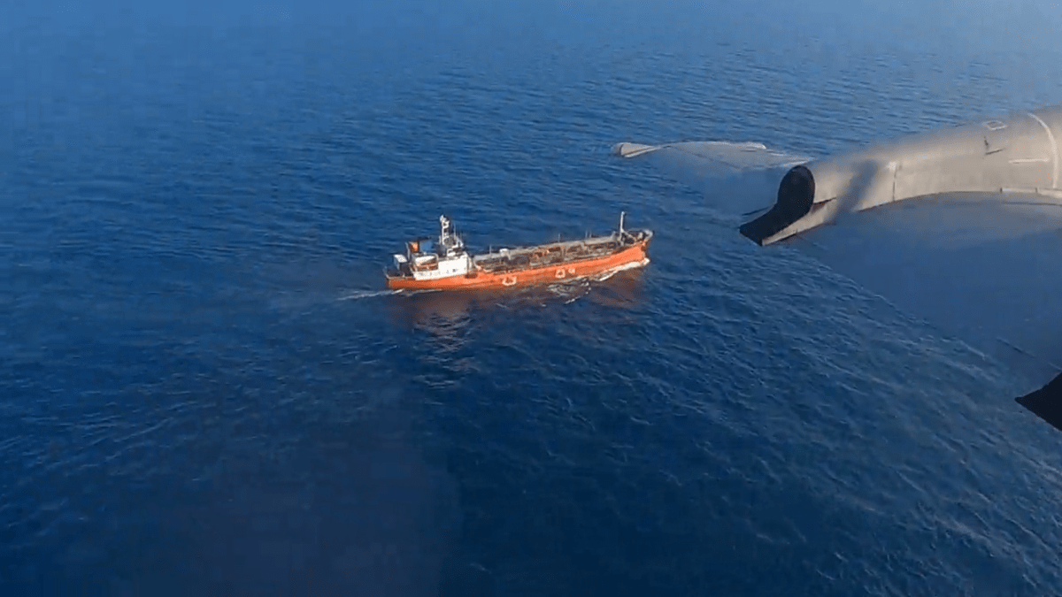 A ship is seen on the ocean with a plane wing in the foreground