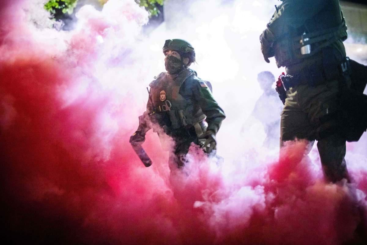 Police and federal officers throw gas canisters to disperse protesters near a U.S. Immigration and Customs Enforcement facility in Portland, Ore. on Sunday, Oct. 5, 2025.