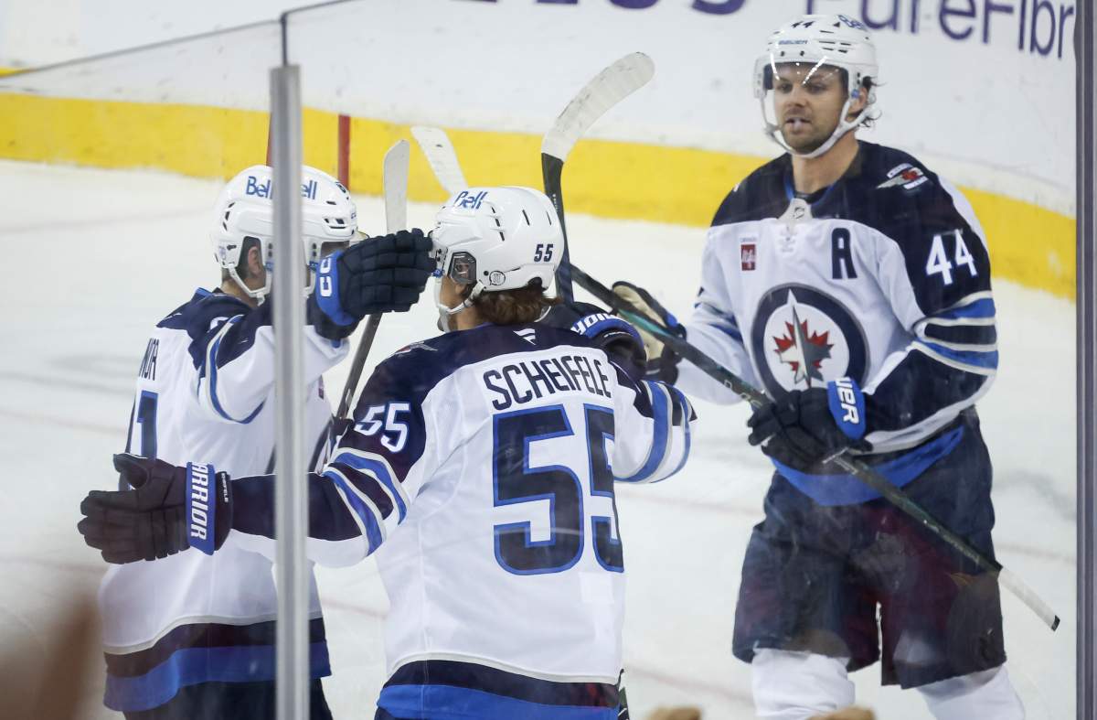Winnipeg Jets' Mark Scheifele, centre, celebrates his goal with teammates during third period NHL hockey action against the Calgary Flames in Calgary, Alta., Monday, Oct. 20, 2025. THE CANADIAN PRESS/Jeff McIntosh.
