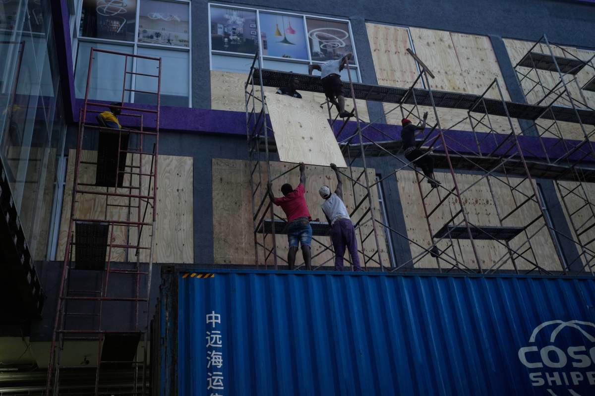 Workers board up shop windows ahead of Hurricane Melissa's forecast arrival in Kingston, Jamaica, Sunday, Oct. 26, 2025.