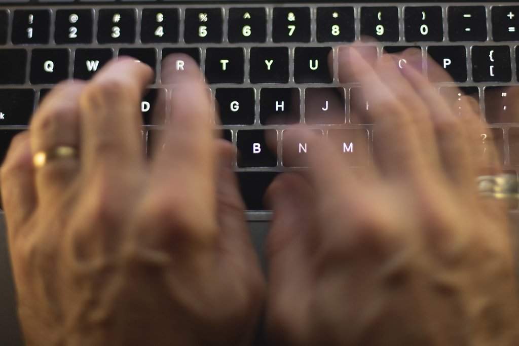 FILE: Hands type on a computer keyboard. 